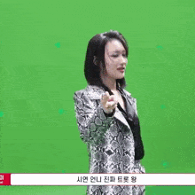 a woman wearing a snake print coat is standing in front of a green screen