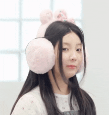 a young girl wearing a pair of pink ear warmers looks at the camera .