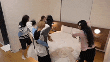 a group of girls are playing with pillows in a bedroom