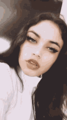 a woman with long dark hair is taking a selfie with her mouth open .