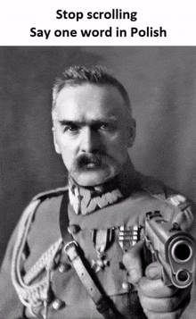 a man with a mustache is holding a gun with the words stop scrolling say one word in polish below him