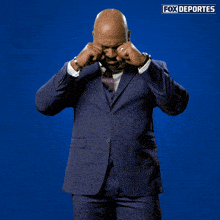 a man in a suit and tie is dancing in front of a blue background with fox deportes written on it