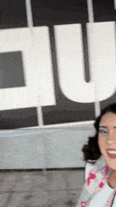 a woman smiles in front of a large u