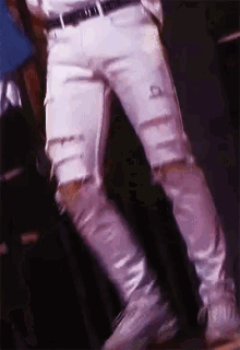 a close up of a person 's legs wearing white jeans and white sneakers .
