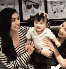 a woman is holding a baby in her arms while another woman smiles .