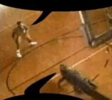 a man is playing basketball on a court with a lizard .