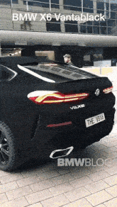 a black bmw x6 vantablack is parked on the sidewalk