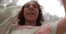 a man with curly hair is riding a water slide and taking a picture of himself .