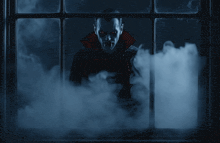 a vampire is looking out of a window with smoke behind him