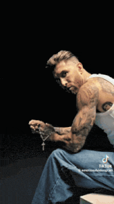 a man with a tattoo on his arm is sitting in front of a screen that says ' not '