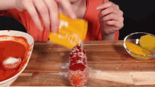a person is putting ketchup on a hot dog
