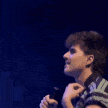 a man is holding a microphone in his hand on a stage .