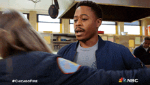 a man in a blue jacket is hugging a woman in a grey shirt with the nbc logo on the bottom