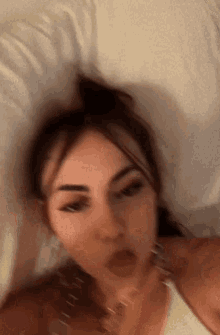 a woman is laying on a bed taking a selfie .