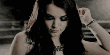 a woman with long black hair is wearing a bracelet on her wrist