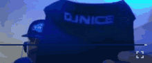 a man wearing a hat and headphones is standing in front of a blue box that says dunice