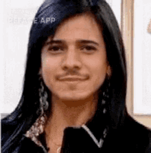 a man with long black hair and a mustache is wearing earrings .