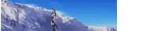 a person standing on top of a snow covered mountain with a blue sky in the background