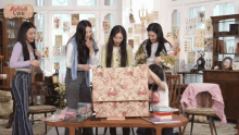 a group of girls standing around a table with a sign that says ' red velvet '