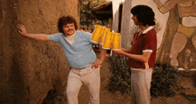 two men are standing next to each other holding cups in their hands