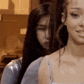 two women are standing next to each other in a room and one of them is looking at the camera .