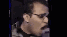 a close up of a man wearing sunglasses yawning .
