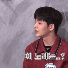 a young man in a red jacket has a name tag around his neck that says ?