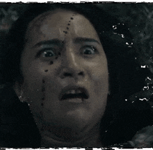a woman with blood on her face is making a scary face