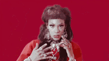a woman wearing a red sweater and a necklace with the word rico on it