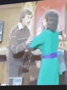 a woman in a green dress stands next to a man in a brown shirt