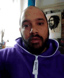 a bald man with a beard wearing a purple moritz hoodie
