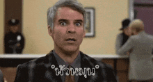 a man in a suit and tie is making a funny face while standing in front of a counter .