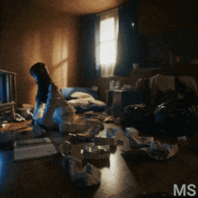a woman sits on the floor in a messy room with ms written on the bottom right