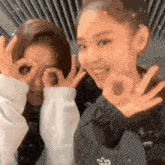 two girls are posing for a picture and one of them is wearing a black jacket