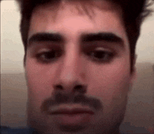 a close up of a man with a mustache making a funny face .