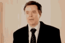 a man in a suit covering his face with his hands .
