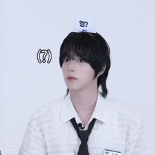 a young man wearing a white shirt and black tie has a card on his head that says ' ? '