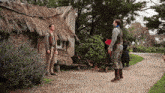 a group of people standing in front of a thatched roof building