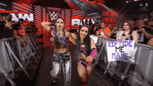 two female wrestlers holding a sign that reads riptide me mami