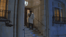 a man in a white coat is running down stairs at night
