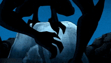 a silhouette of a monster with a claw on a rock in the dark