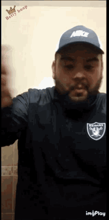 a man wearing a raiders jersey and a nike hat