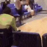 a group of people are sitting in a waiting room with purple chairs .