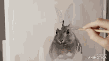 a person is painting a rabbit on a canvas .
