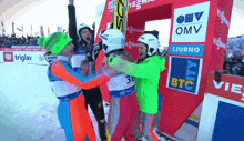 a group of skiers celebrate in front of a sign that says omv ljubno