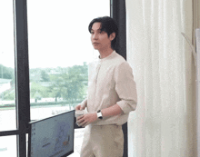 a man stands in front of a window holding a cup