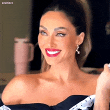 a woman wearing red lipstick and earrings is smiling for the camera .