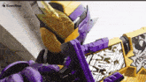 a kamen rider holding a purple and gold item
