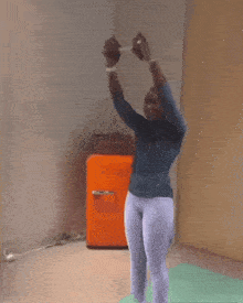 a person is standing on a yoga mat in front of an orange refrigerator