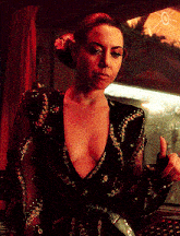 a woman in a black dress with a flower in her hair is giving a thumbs up sign .